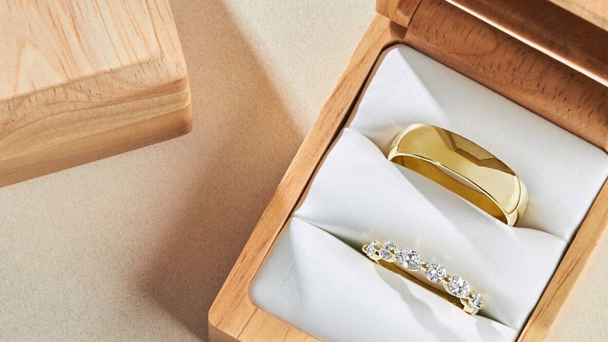 Men's and Women's yellow gold wedding bands in a wooden ring box.